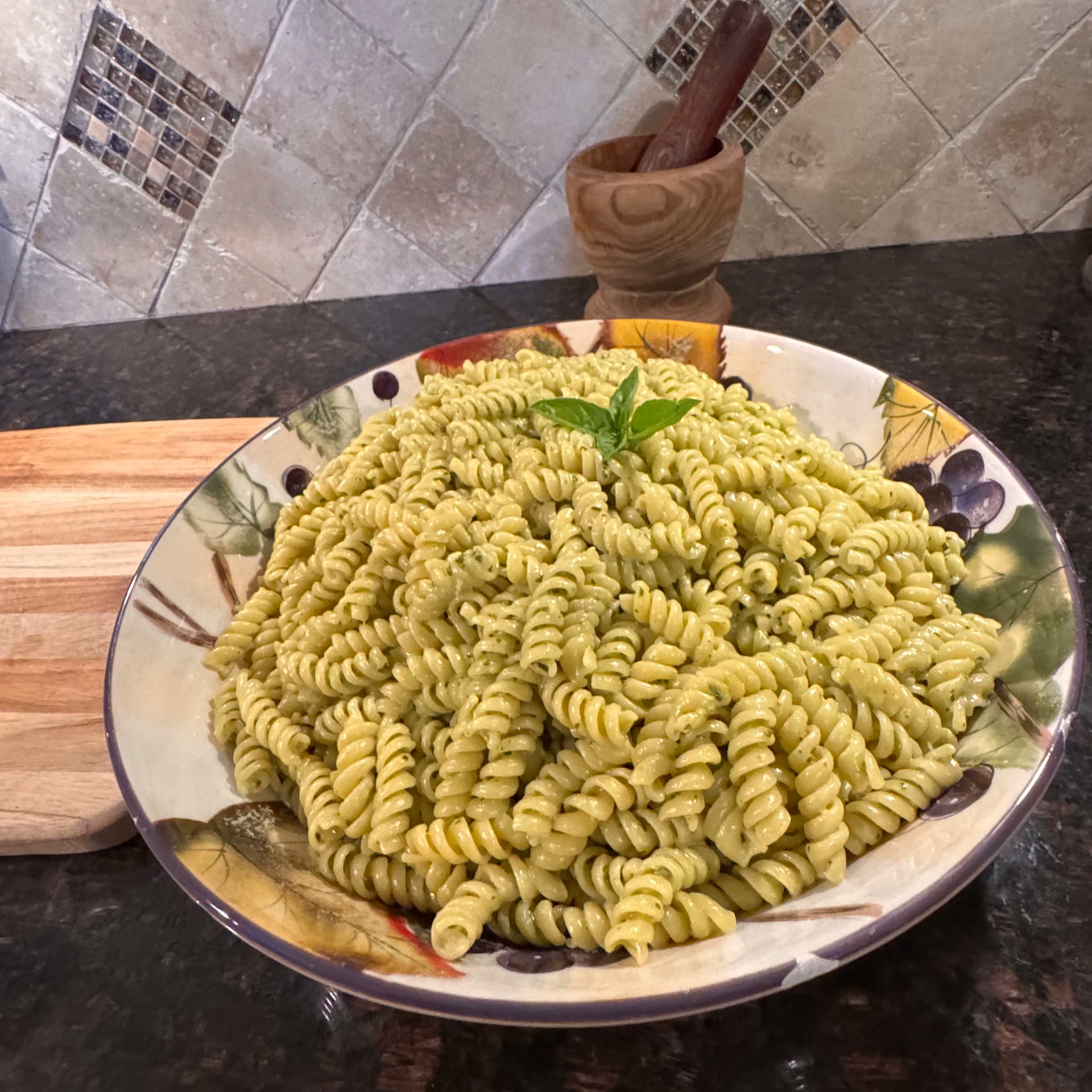 Basil pesto rotini in a ceramic bowl with fresh basil and shaved parmesan